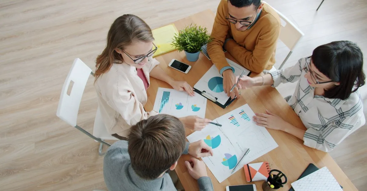 Equipe analisando dados de campanhas em smartphones e gráficos